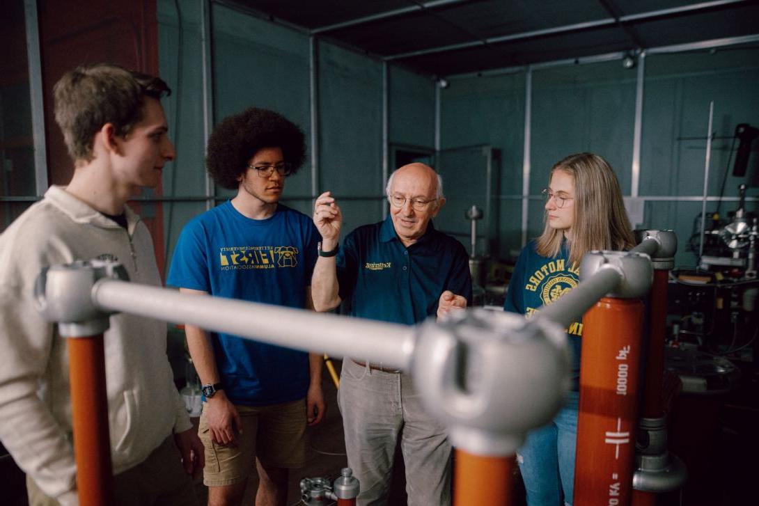 A Kettering professor explains electrical engineering concepts to three students in the High Voltage Lab